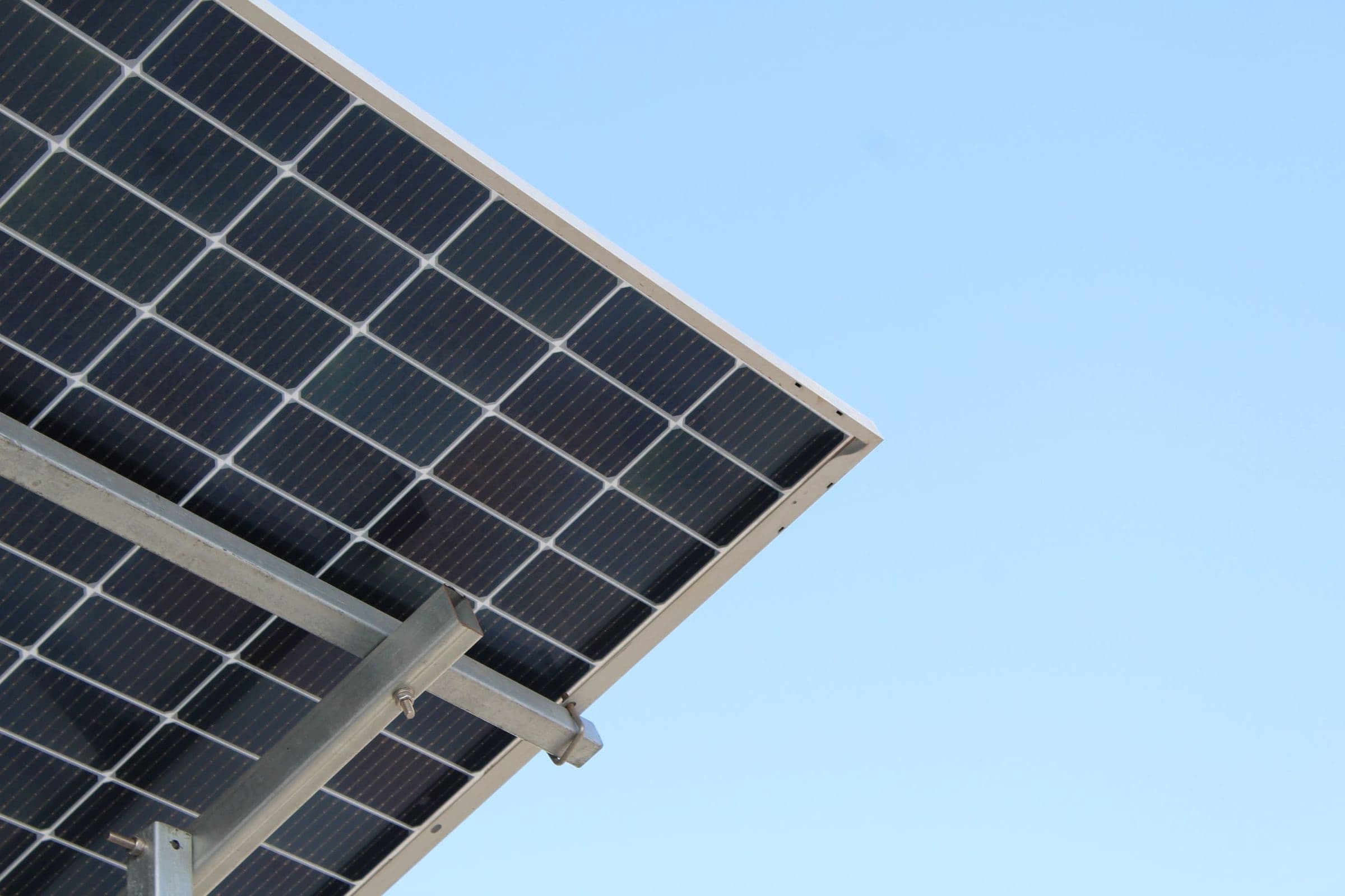 The underside of a solar panel on a galvanised mounting structure against a clear sky